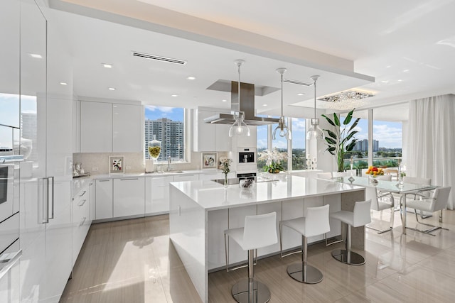 kitchen featuring a center island, white cabinetry, island exhaust hood, and hanging light fixtures