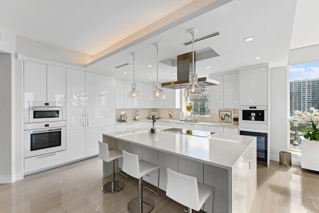 kitchen featuring white cabinetry, island exhaust hood, black electric cooktop, pendant lighting, and a breakfast bar