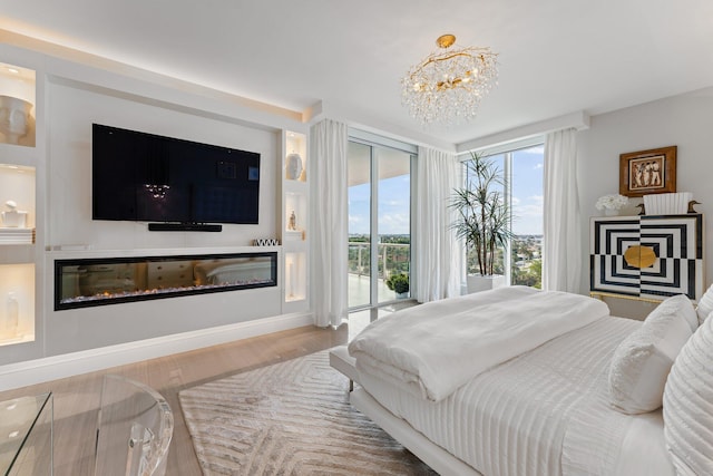 bedroom with hardwood / wood-style flooring, access to exterior, and a notable chandelier