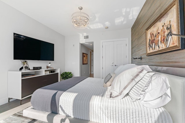 bedroom featuring light hardwood / wood-style floors, a closet, a chandelier, and wooden walls