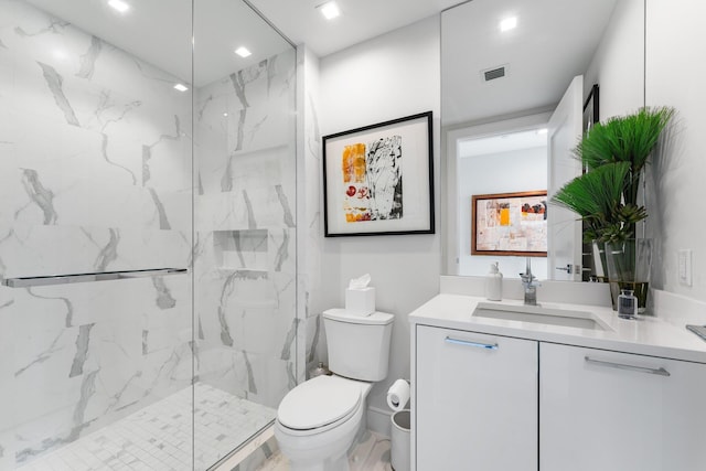 bathroom with a tile shower, toilet, and vanity