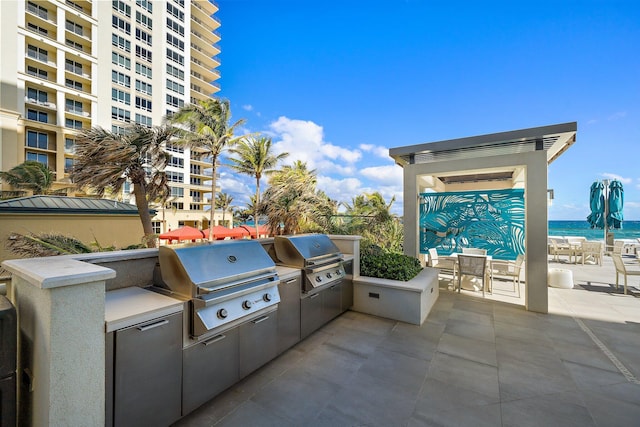 view of patio featuring area for grilling, a water view, and a grill