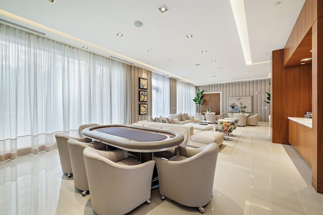 recreation room with light tile patterned floors, wooden walls, and a healthy amount of sunlight