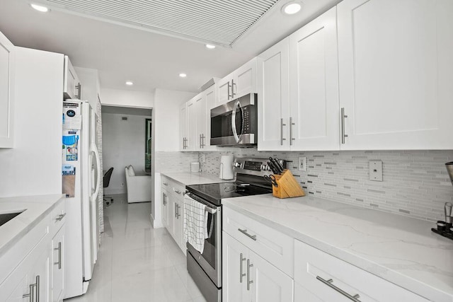 kitchen featuring white cabinets, light tile patterned floors, appliances with stainless steel finishes, tasteful backsplash, and light stone counters