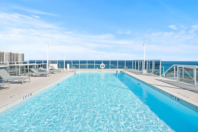 view of pool featuring a water view and a patio