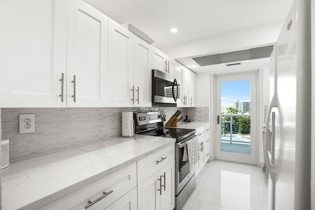 kitchen with white cabinets, stainless steel appliances, light stone counters, and tasteful backsplash