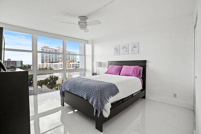 tiled bedroom with ceiling fan and a wall of windows