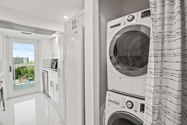 laundry room featuring light tile patterned flooring and stacked washer / drying machine