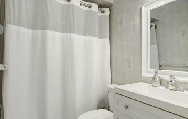 bathroom with vanity, toilet, and tile walls