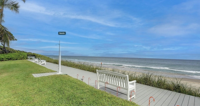 surrounding community featuring a water view, a yard, and a view of the beach