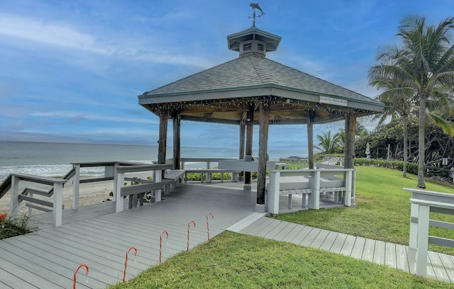 dock area with a gazebo, a water view, and a lawn