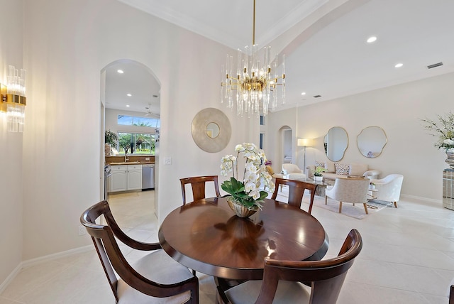 tiled dining room with ornamental molding, sink, and a chandelier