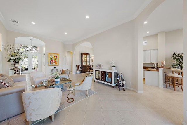 tiled living room featuring a chandelier, french doors, and crown molding