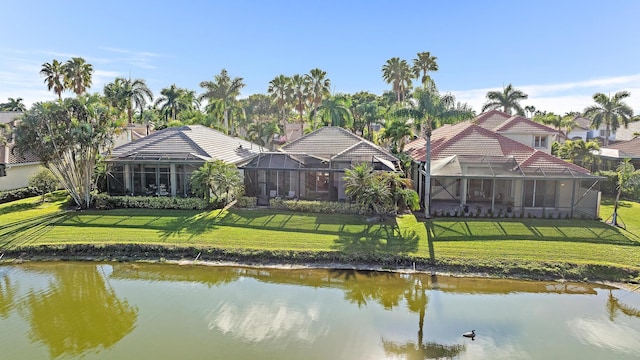 rear view of house with a water view, a lanai, and a lawn