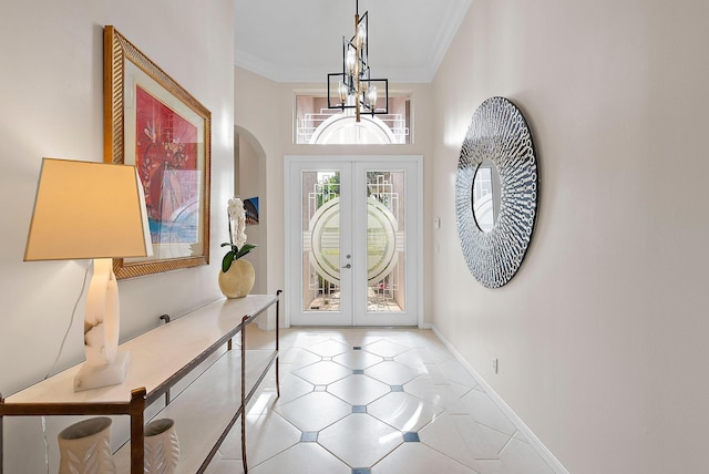 entrance foyer featuring crown molding, french doors, a chandelier, and a high ceiling