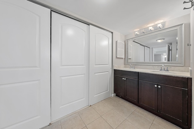 full bathroom with double vanity, tile patterned flooring, and a sink