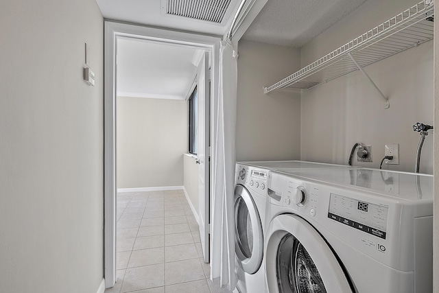 clothes washing area featuring light tile patterned floors, laundry area, visible vents, baseboards, and washing machine and dryer