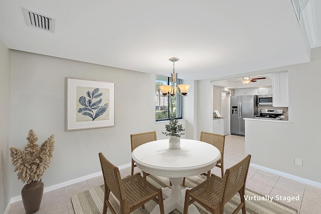 dining space with light tile patterned floors, ceiling fan with notable chandelier, visible vents, and baseboards