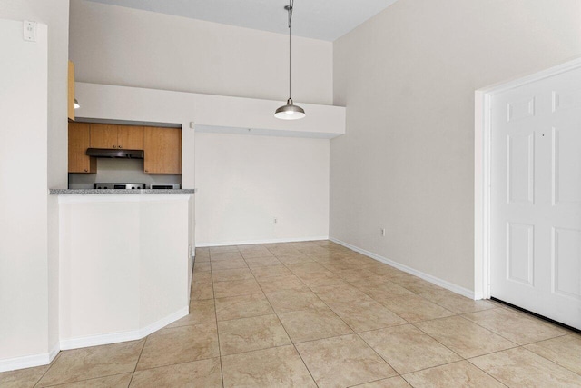 kitchen with pendant lighting, light tile patterned flooring, and a high ceiling