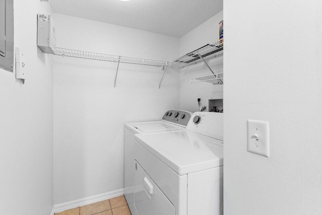 laundry room featuring separate washer and dryer, a textured ceiling, and light tile patterned floors