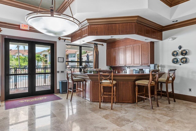 interior space with french doors, a breakfast bar, crown molding, and kitchen peninsula