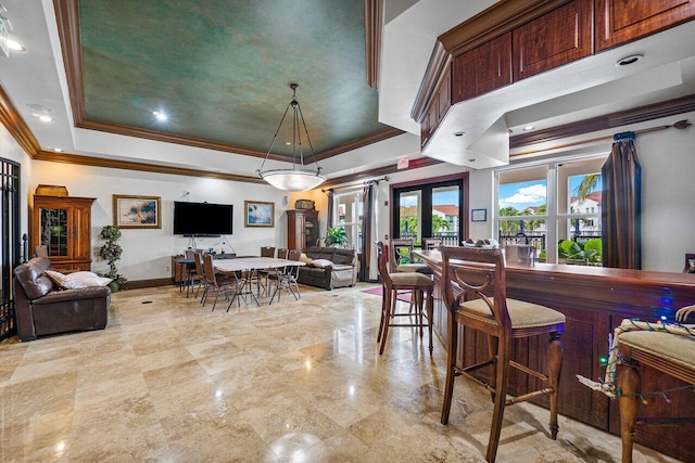 interior space featuring a raised ceiling, crown molding, a breakfast bar area, and french doors