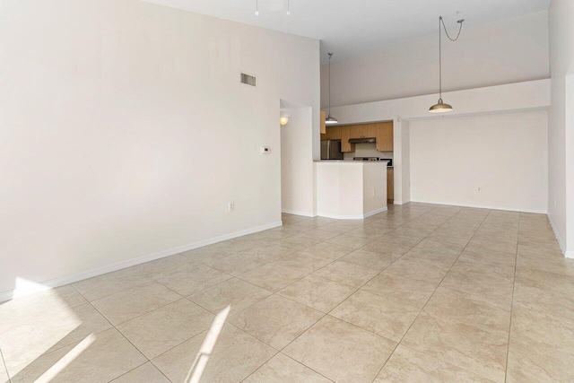 unfurnished room featuring light tile patterned flooring and a towering ceiling