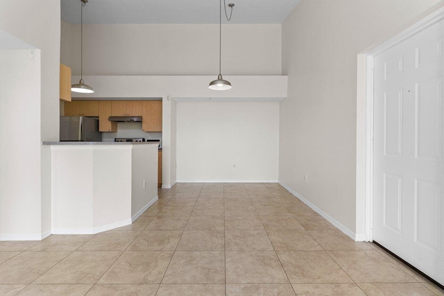 kitchen with pendant lighting, light tile patterned floors, stainless steel fridge, and a high ceiling