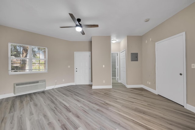 unfurnished living room with a wall mounted air conditioner, ceiling fan, light hardwood / wood-style floors, and electric panel