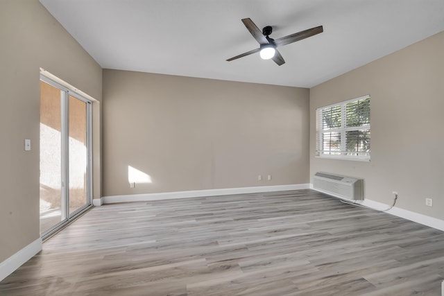 empty room featuring a wall mounted air conditioner, ceiling fan, and light hardwood / wood-style floors