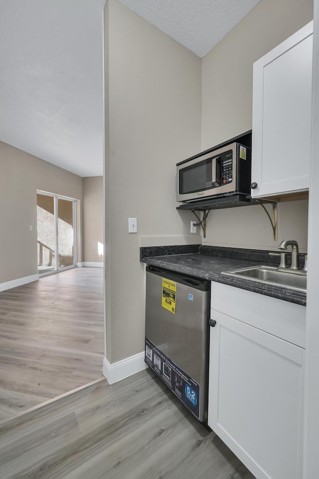 kitchen featuring light wood-type flooring, stainless steel appliances, white cabinetry, and sink