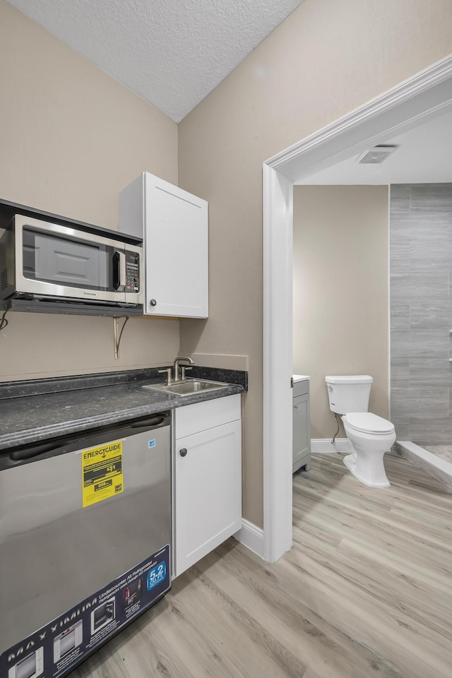 kitchen with white cabinetry, light wood-type flooring, a textured ceiling, and appliances with stainless steel finishes