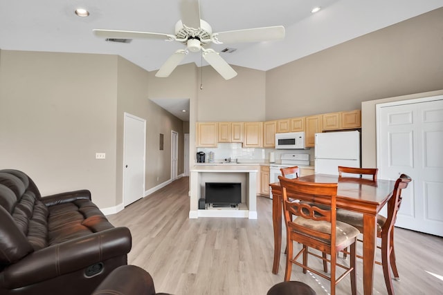 dining room featuring ceiling fan, light hardwood / wood-style floors, sink, and high vaulted ceiling