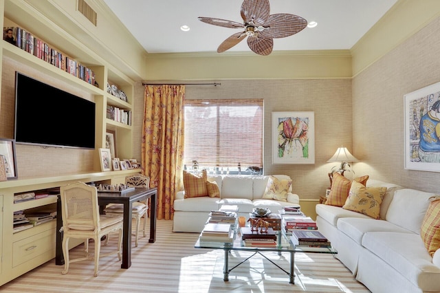 living room with built in shelves, ceiling fan, and crown molding