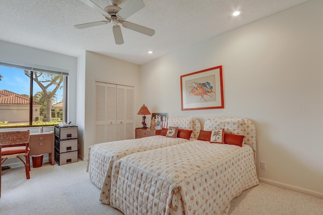 carpeted bedroom with ceiling fan, a textured ceiling, and a closet