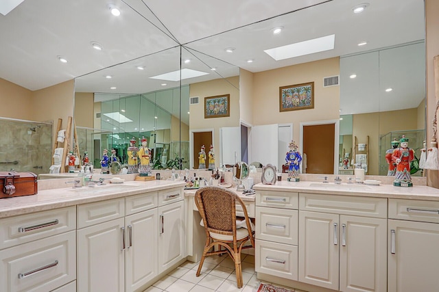 bathroom with tile patterned flooring, vanity, a shower with shower door, and a skylight