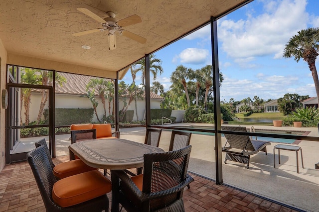 sunroom / solarium with ceiling fan and a water view