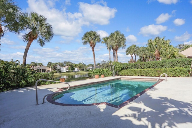 view of swimming pool featuring a patio and a water view