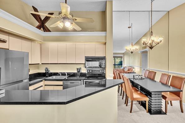 kitchen with hanging light fixtures, stainless steel appliances, ceiling fan with notable chandelier, and sink