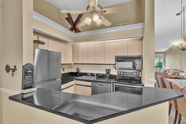 kitchen featuring sink, kitchen peninsula, crown molding, ceiling fan with notable chandelier, and appliances with stainless steel finishes