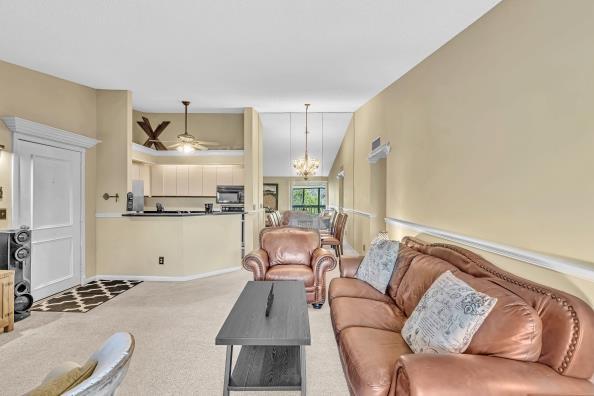 carpeted living room featuring ceiling fan with notable chandelier