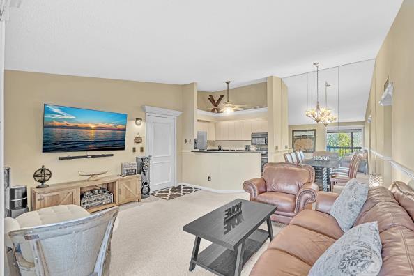 living room featuring carpet flooring, ceiling fan with notable chandelier, and lofted ceiling