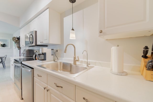 kitchen with hanging light fixtures, white cabinetry, appliances with stainless steel finishes, and sink