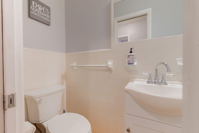 bathroom with vanity, tile walls, and toilet