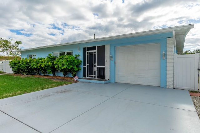 ranch-style home with brick siding, an attached garage, driveway, and fence