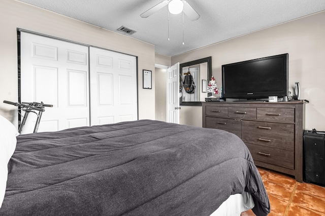 bedroom featuring ceiling fan, light tile patterned floors, and a textured ceiling