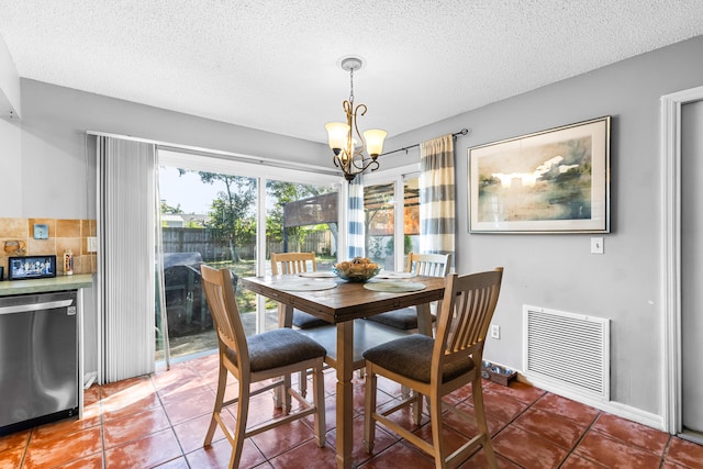 tiled dining space featuring a textured ceiling and an inviting chandelier