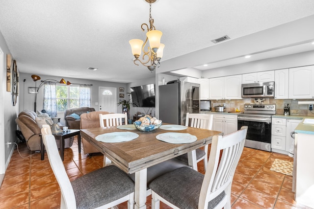 dining room featuring light tile patterned floors, a textured ceiling, and an inviting chandelier