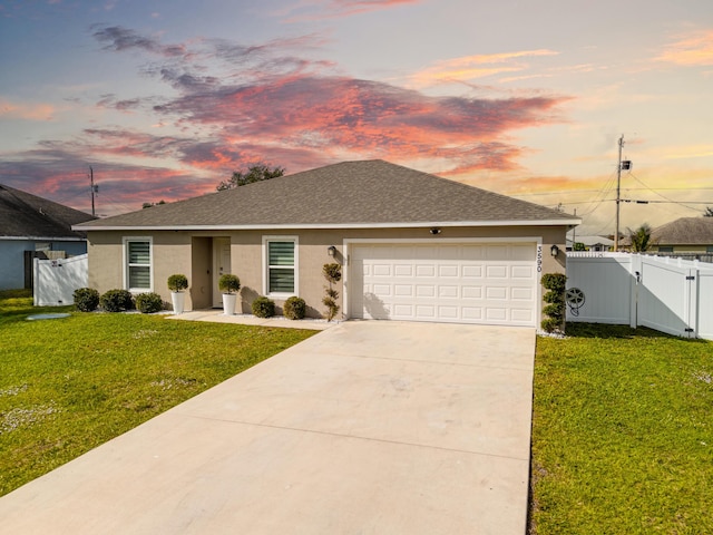 single story home featuring a garage and a lawn