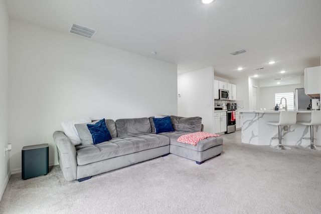 living room with sink and light colored carpet